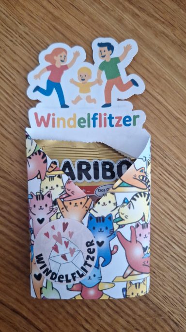kleine Verpackung mit Aufmerksamkeit Packung mit bunten Süßigkeiten, dekoriert mit Figuren und dem Aufdruck "Windelflitzer".