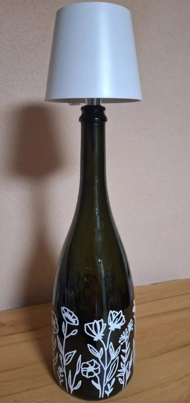 Upcycling Glasflasche mit floralem Design, darauf eine weiße Lampenschirm.