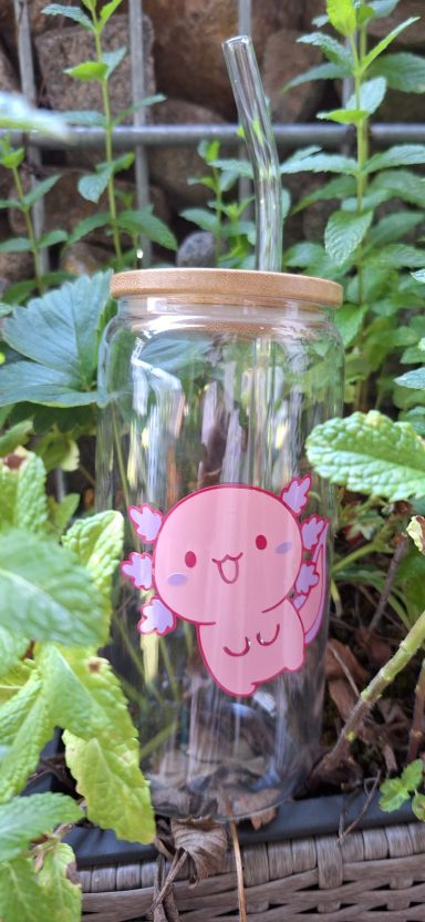 Trinkglas mit Axolotl Glasbehälter mit einem süßen, pinken Axolotl-Aufkleber, umgeben von Pflanzen.