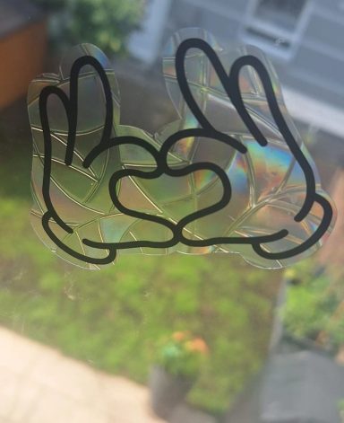 Fensterbild Zwei Hände formen ein Herz, mit buntem holographischen Effekt.